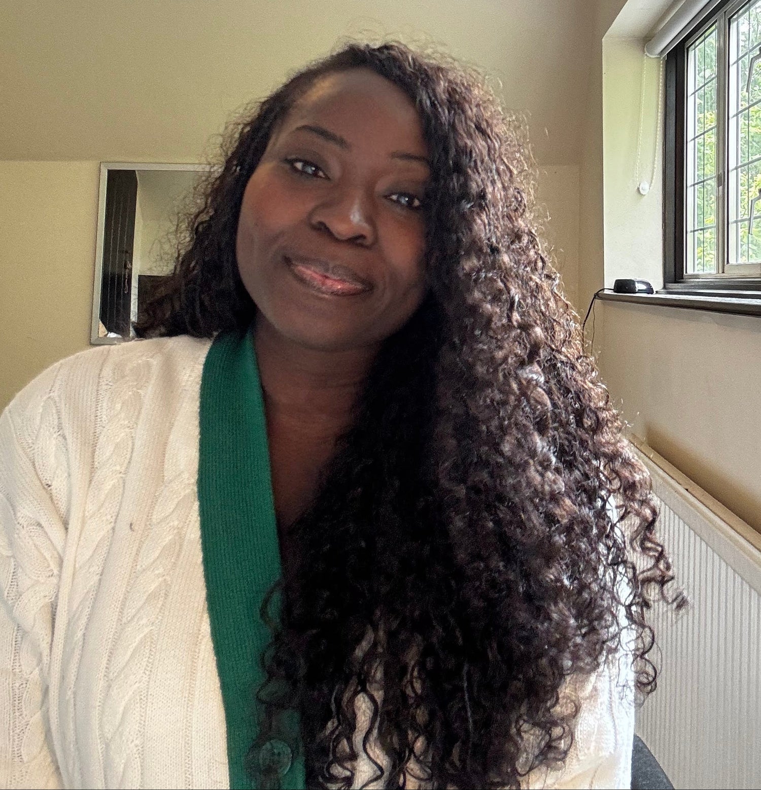 our female founder . a woman with long, curly hair in a room with a window and light fixture.